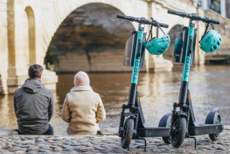 Photograph of two people sitting next to Tier e-scooters