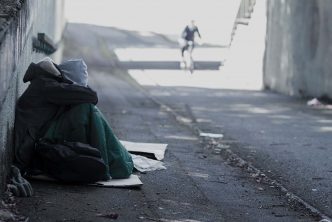 A photograph of a homeless person sitting on the street