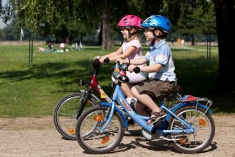A photograph of two children riding bicycles
